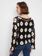 Load image into Gallery viewer, Woman wearing a black crochet sweater with white daisy patterns and blue jeans on a plain background.

