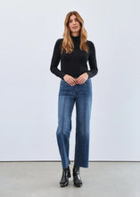 Load image into Gallery viewer, Woman wearing a black mock neck top, blue jeans and black boots against a white background.
