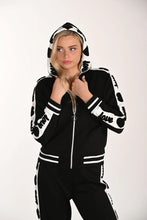 Load image into Gallery viewer, Woman wearing a black and white patterned jacket with hoodie and matching pant on a white background.
