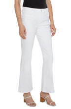 Load image into Gallery viewer, Model wearing white denim bootcut jeans with welt pockets, white sandals and black top against a white background.
