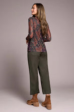 Load image into Gallery viewer, Woman wearing a patterned long-sleeve mesh top, green pants and brown boots against a plain background.
