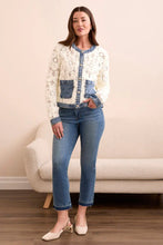 Load image into Gallery viewer, Woman wearing an eggshell cardigan with blue denim accents, blue jeans and beige heels standing in a room. 
