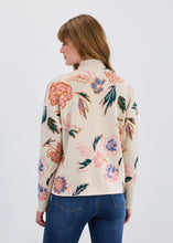 Load image into Gallery viewer, Woman wearing a floral patterned sweater and blue jeans against a plain background.
