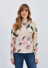 Load image into Gallery viewer, Woman wearing a floral patterned sweater and blue jeans against a white background.
