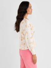 Load image into Gallery viewer, Woman wearing a cream sweater with pastel abstract print and pink pants against a white background.
