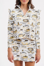Load image into Gallery viewer, A woman modeling a matching long-sleeve collared top and skort set with a white base and gold and black graphic print, set against a plain light gray background.
