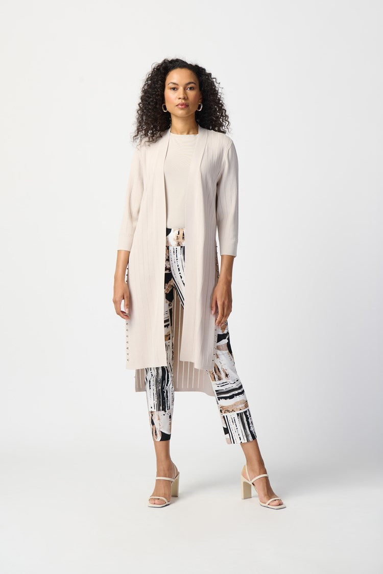 This stylish cover-up/cardigan features extended side openings and flared sleeves that impart a sense of fluidity and grace while in motion. The decorative studs along the openings add a touch of bold sophistication, making it perfect for both professional and casual settings.  Color- Moonstone. Drape silhouette. No pockets. No zipper. Not lined. Side splits lined with silver hardware.
