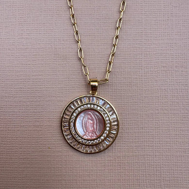 Gold necklace with a circular pendant featuring a religious icon on a beige background