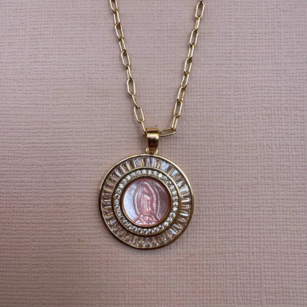 Gold necklace with a circular pendant featuring a religious icon on a beige background