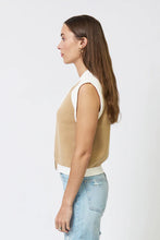Load image into Gallery viewer, Woman wearing a sand-colored sleeveless sweater vest with beige pants on a plain background.
