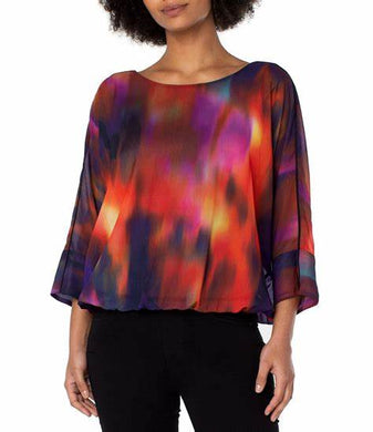 Featuring mesmerizing northern lights print in red, purple/blue, yellow and black, this top is sure to turn heads. Its dolman sleeves and tie back detail add to its charm — perfect for brunch or special occasions, it looks great when paired with denim or trousers.  `Colors-Northern lights - Splashes of red, purple/blue, yellow and black. Chiffon fabrication Round neckline. 3/4 dolman sleeves. Northern light print. Tie back detail. Gathered hemline.