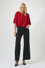 Load image into Gallery viewer, Woman wearing a red fringe sweater, black sparkle pants and black heels against a white background.
