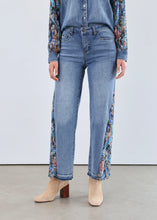 Load image into Gallery viewer, Woman in denim shacket with floral sleeves, jeans with floral side inserts and tan boots against a white background.
