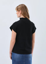 Load image into Gallery viewer, Woman wearing a black cap sleeve, mock neck top and blue jean skirt against a light gray background.
