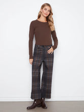 Load image into Gallery viewer, A woman modeling a brown long-sleeve crewneck top and dark brown plaid wide-leg trousers with brown leather boots, standing against a white wall.
