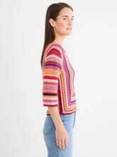 Load image into Gallery viewer, Woman wearing a red multicolor striped three-quarter sleeve sweater and blue jeans against a light grey background.
