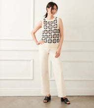 Load image into Gallery viewer, Woman wearing a sleeveless floral patterned crochet top, cream-colored pants and black sandals against a white background. 
