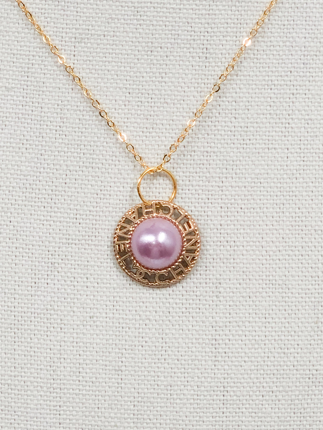 A stunning pink pearl glistens in a gold setting with the words CHANEL and the CC logo surrounding the pearl in a circle.  A sweet addition to your jewelry collection, this gorgeous piece is rare and unique. This necklace is an attention grabber!  Color- Pink and gold. Vintage Coco Chanel button. Pendant length with bale- 1 inch. 18-inch diamond cut flat gold chain. Lobster clasp. Composition- 16k gold plating over brass. Handmade re-purposed jewelry.