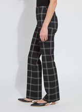 Load image into Gallery viewer, Model wearing black and off-white plaid pants and black flats standing against a white background.
