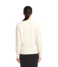 Load image into Gallery viewer, Woman wearing a cream v-neck  sweater with pearls and black skirt against a white background.
