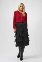 Load image into Gallery viewer, Woman wearing a red cardigan and black tiered fringe skirt and black boots against a light background.
