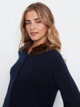 Load image into Gallery viewer, A woman wearing a navy blue knit cardigan with a brown faux-fur collar, photographed against a plain white studio background.
