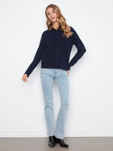 Load image into Gallery viewer, A woman modeling a dark navy blue cardigan with faux fur collar paired with light-wash blue jeans and black ankle boots, standing against a plain white wall.
