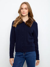 Load image into Gallery viewer, A woman wearing a navy blue knit cardigan sweater with a brown and black leopard-print faux fur collar, paired with blue jeans, against a plain white studio background.
