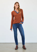 Load image into Gallery viewer, Woman wearing a bronze sweater with blue trim, blue jeans and brown boots against a white background.
