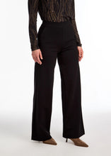 Load image into Gallery viewer, Woman wearing a black metallic top, black pants and brown boots against a white background.
