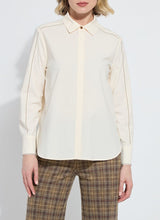 Load image into Gallery viewer, Model wearing a cream-colored long sleeve blouse with bronze embellishments and brown plaid pants against a white background.
