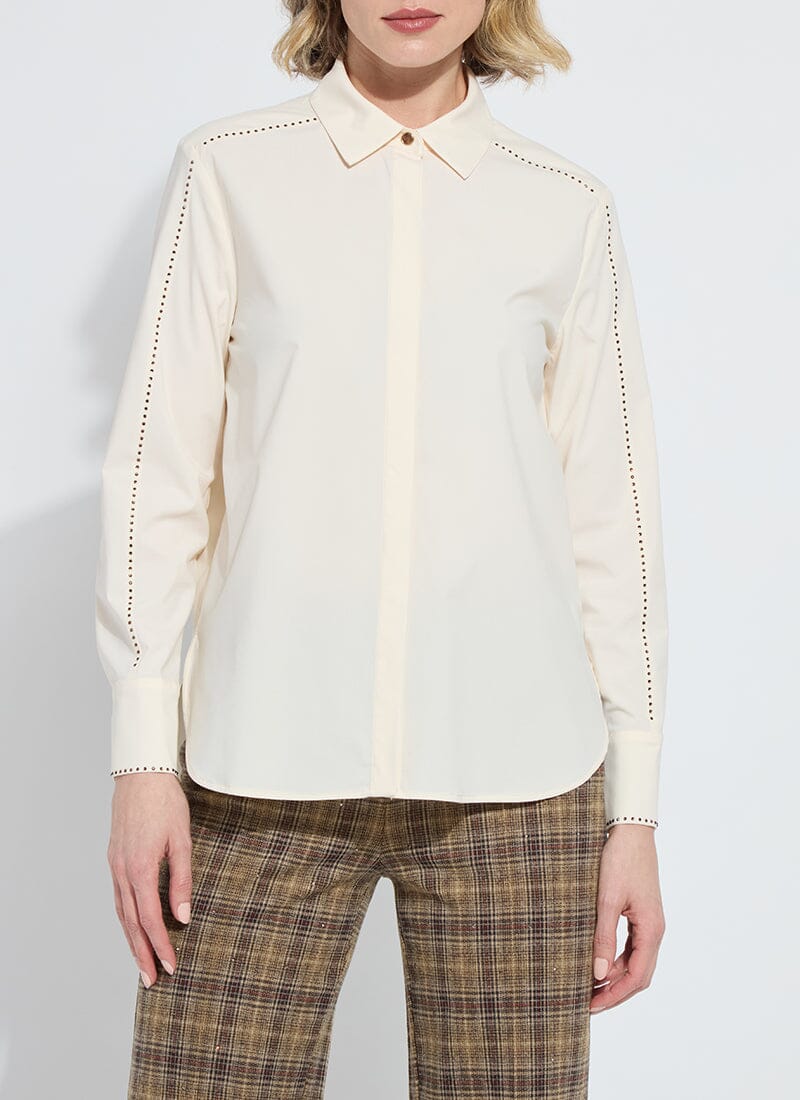 Model wearing a cream-colored long sleeve blouse with bronze embellishments and brown plaid pants against a white background.