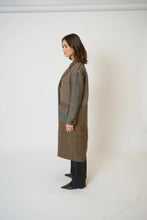 Load image into Gallery viewer, Woman wearing a long brown patchwork coat, jeans and boots against a white background.
