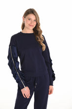 Load image into Gallery viewer, Woman wearing a navy blue ruffled sleeve with zippers top and navy blue pants against a white background.
