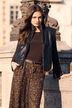 Load image into Gallery viewer, Woman wearing a reversible black and cheetah vest, brown top and cheetah pants standing outdoors against a concrete ledge.
