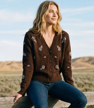 Load image into Gallery viewer, A woman sits on a wooden fence in a desert landscape wearing a dark brown knit cardigan with rhinestone floral embroidery and blue jeans.
