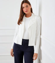 Load image into Gallery viewer, Woman wearing an off-white jacket over an off-white top and blue jeans standing in front of a door with an archway.
