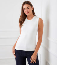Load image into Gallery viewer, Woman wearing an off-white sleeveless tank top and dark pants against a light background.
