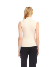 Load image into Gallery viewer, Woman wearing a beige sleeveless turtleneck sweater and black pants against a white background.
