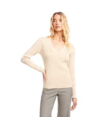 Woman wearing a beige sweater and plaid pants against a white background.