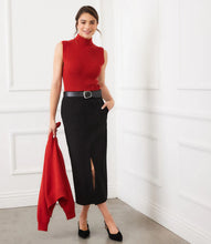 Load image into Gallery viewer, Woman wearing a red sleeveless ribbed turtleneck sweater, red cardigan, black skirt, black belt and black heels against a white wall.
