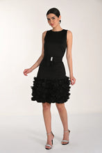 Load image into Gallery viewer, Woman wearing a black dress with a ruffled hem and silver heels on a white background.
