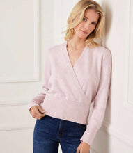 Load image into Gallery viewer, Woman wearing a light pink sweater and blue jeans against a white wall.

