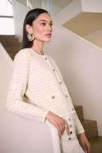 Load image into Gallery viewer, Woman wearing a winter white and gold sequined textured cardigan and winter white pants with gold buttons in an indoor setting.
