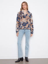 Load image into Gallery viewer, A woman modeling a long-sleeve button-up coat with a camel, navy, and white abstract floral pattern, paired with light-wash blue jeans and black ankle boots, standing against a white wall.
