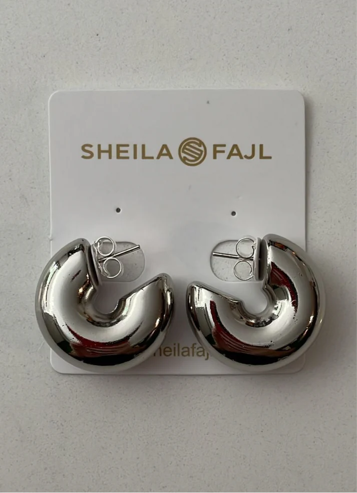 The Small Bubble Hoops by Sheila Fajl are a stylish and elegant accessory. These hoops are handmade in Brazil and feature a unique bubble design. They are crafted from silver-plated nickel-free brass, ensuring both quality and comfort.