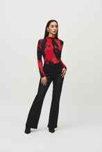 Load image into Gallery viewer, Upgrade your outfit with our silky knit top featuring a vibrant abstract print, long sleeves, and a flattering mock neck. The eye-catching color combination of black and shades of red will surely draw attention.
