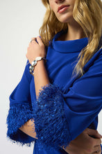 Load image into Gallery viewer, Closeup of a woman wearing a blue dress with fringe cuffs against a white background.
