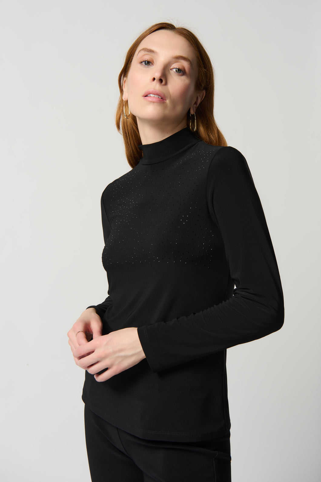 Lightweight and soft on the skin, this figure-flattering top is perfect for pairing with everything in your closet. Featuring long sleeves, a chic mock neck and crystal appliqué, this top provides luxurious comfort while offering an iconic silhouette and French flair.  Color- Black. Silky knit fabric. Mock neck Long sleeves. Crystal appliqué at the front. Unlined. Fabric - 96% Polyester. 4% Spandex.