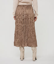 Load image into Gallery viewer, Model wearing a shiny pleated taupe midi skirt, beige sweater and off-white boots against a white background.

